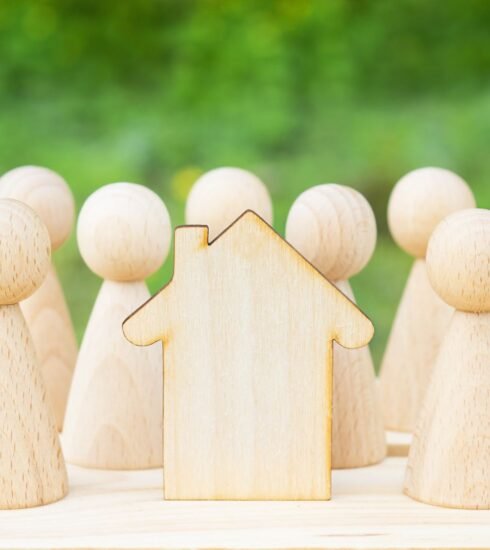 Familienkonzept. Holzhaus mit vielen kleinen Holzfiguren drumherum