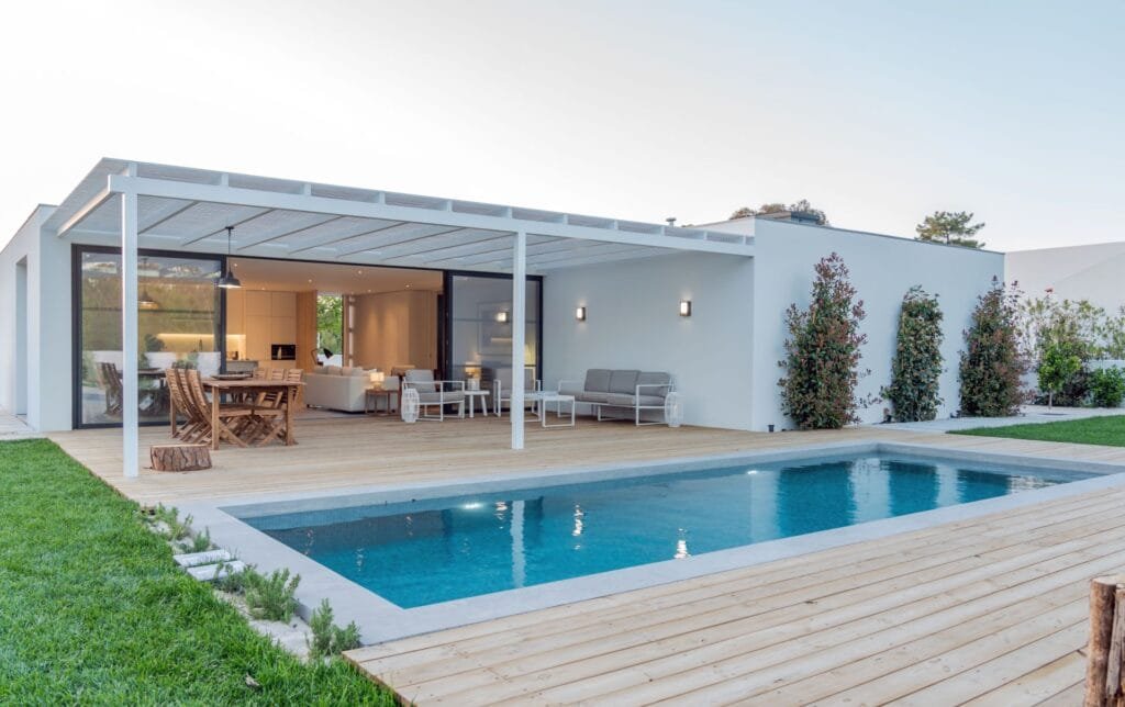 Das Bild zeigt ein weißes einstöckiges Haus mit Pool
