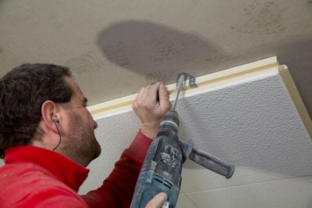 Handwerker befestigt Dämmmaterial an der Kellerdecke 