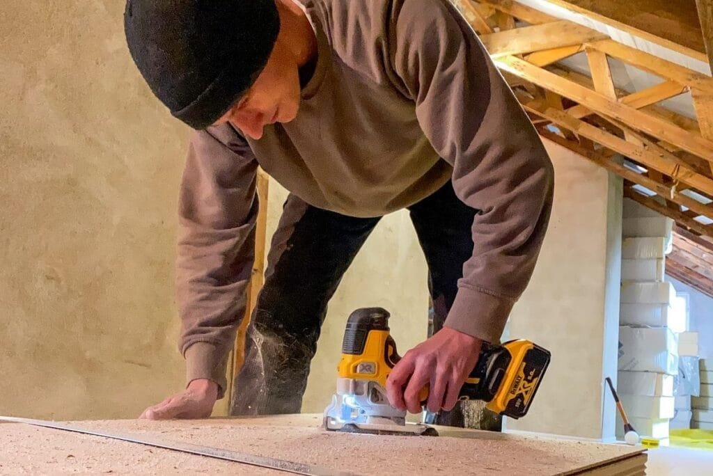 Handwerker schneidet die Dämmplatte mit baustellenüblichem Werkzeug zu