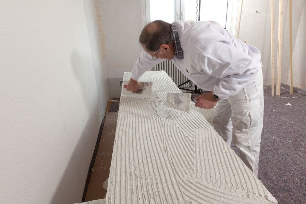 Handwerker trägt Kleber auf einer Platte auf