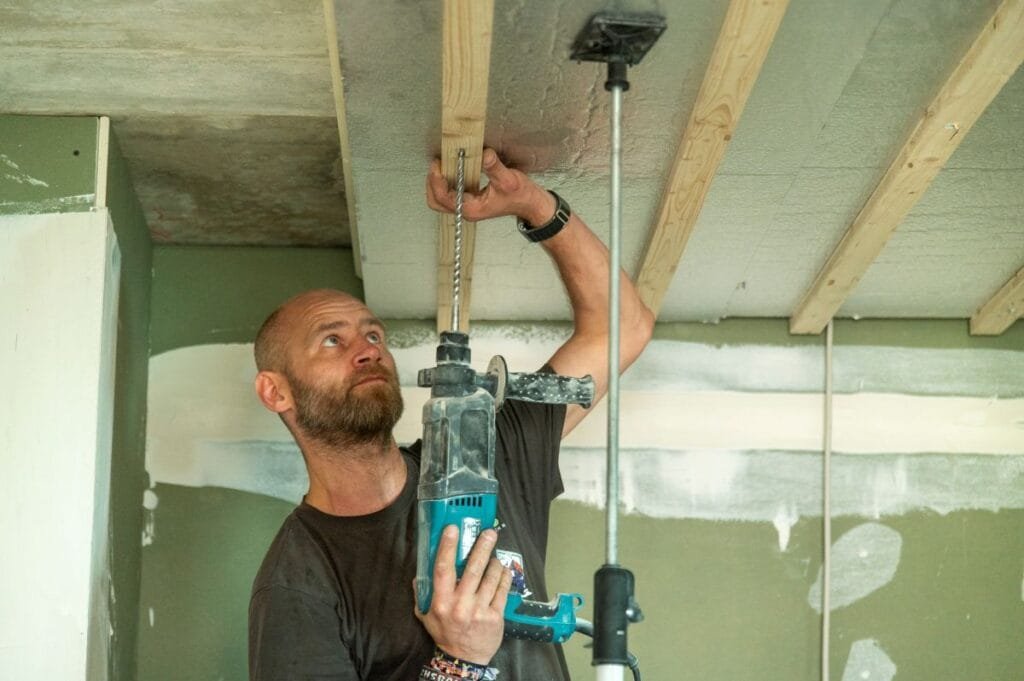 Handwerker schraubt Dämmplatten an Kellerdecke fest