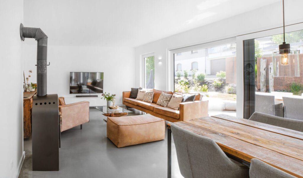 Modernes weißes Wohnzimmer mit grauem Betonfußboden und braunem Sofa.