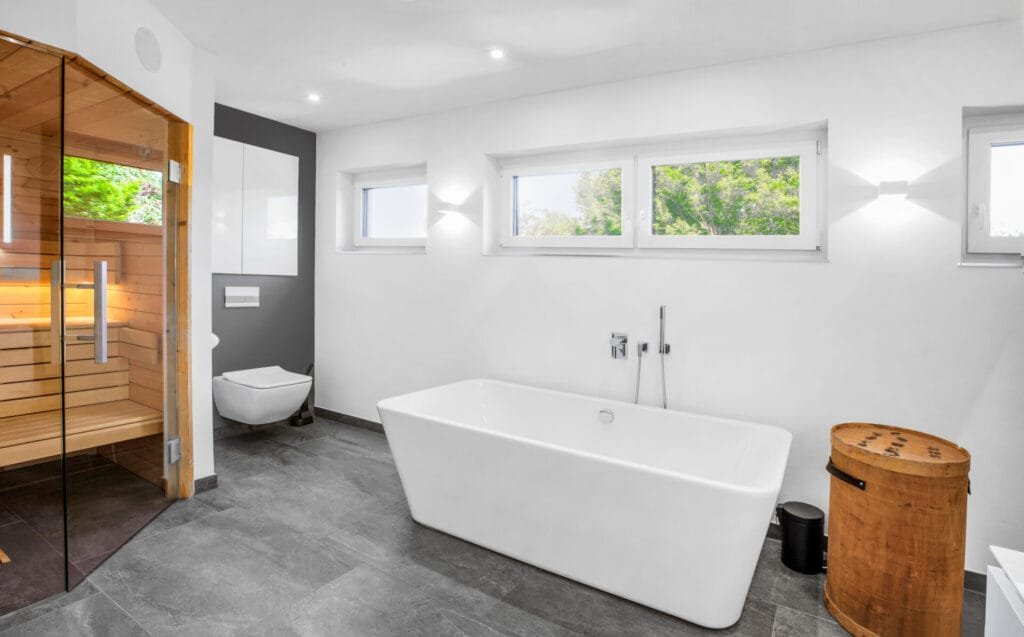 Modernes Bad in anthrazit und weiß mit großer weißer Badewanne und Ecksauna.