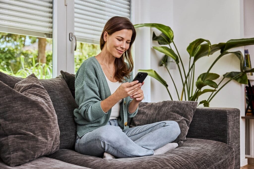 Frau mit Handy auf dem Sofa