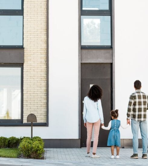 Eine Familie steht mit dem Rücken zur Kamera und sieht zu der schönen Fassade ihres Hauses auf.