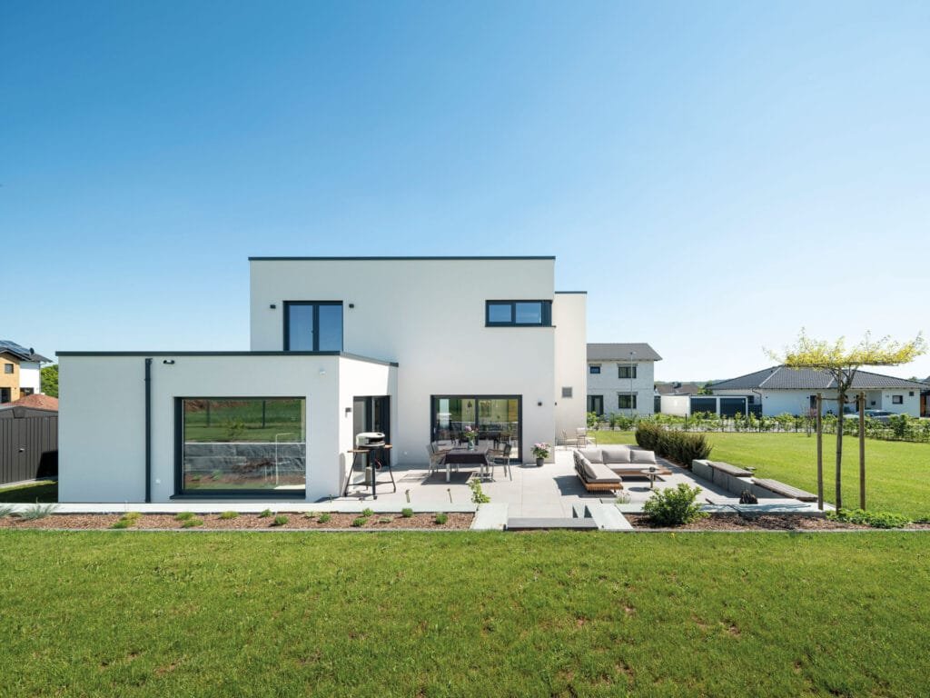 Die Westfassade mit Terrasse der zweigeschossigen individuellen Kundenhausplanung mit Flachdach  von Fingerhaus.