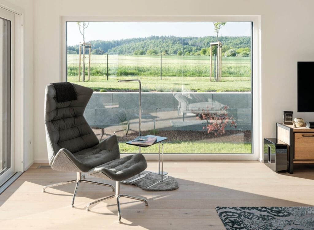 Der Blick aus dem Panoramafenster im Wohnzimmer der zweigeschossigen individuellen Kundenhausplanung mit Flachdach  von Fingerhaus.