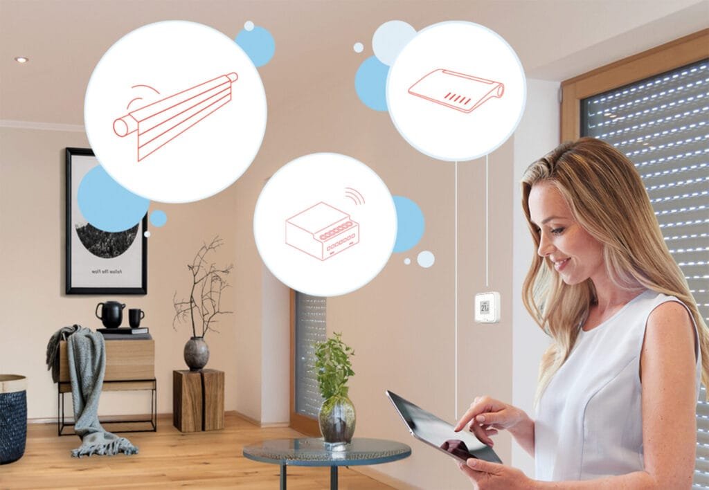 Frau mit Tablet in der Hand steht in einem hellen Wohnzimmer vor heruntergelassenen Jalousien. Smarthome Symbole sind eingeblendet.