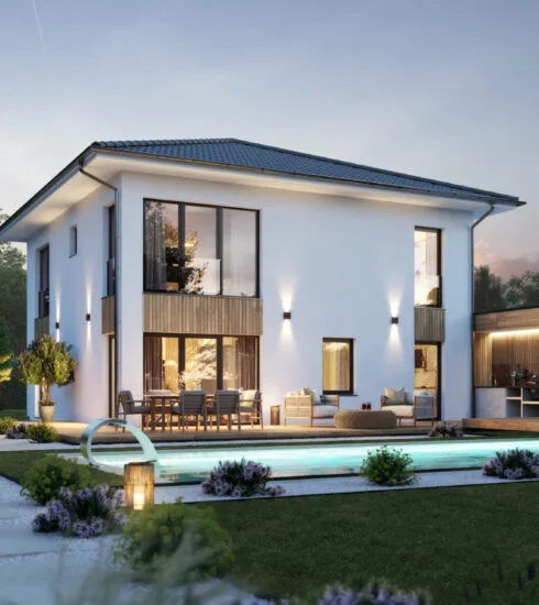 Blick vom Garten aus auf ein erleuchtetes Kampa Haus mit Pool davor.