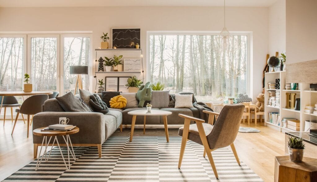 Moderner Wohn-Essbereich mit großen Fenstern, mehreren Regalen und kleinem Kindertisch im Hintergrund