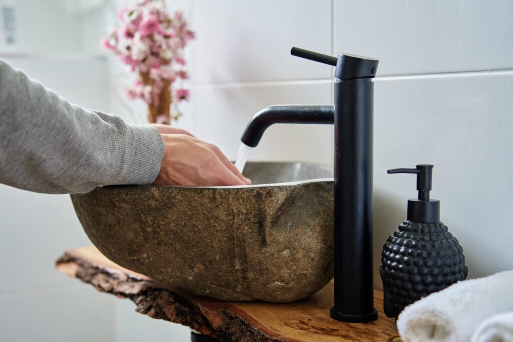 Ein Mann wäscht seine Hände am Waschbecken mit schwarzer Armatur