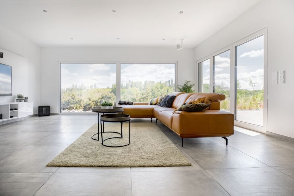 Braunes Ledersofa in hellem Wohnzimmer mit großen Fenstern