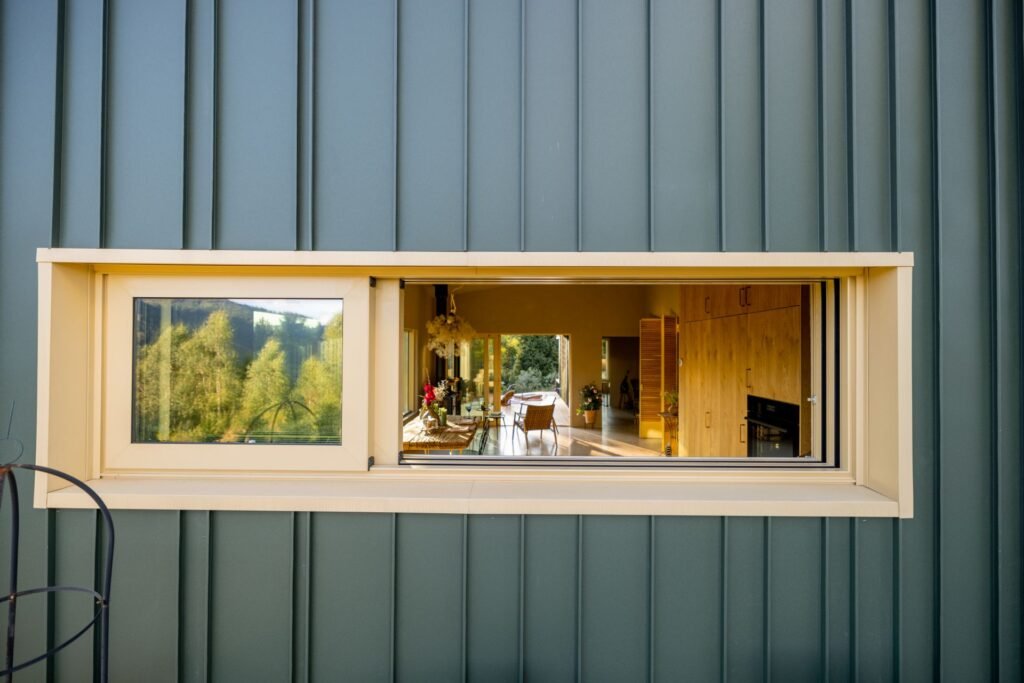 Einblick durch ein liegendes Fensterformat in den Wohnbereich eines lichtdurchfluteten Hauses. Foto: RossHelen/www.elements.envato.com