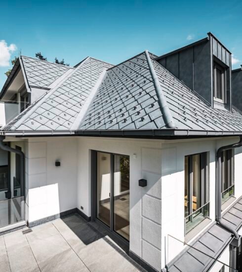 Weißes Haus mit grauem Aluminiumdach bei blauem Himmel und Sonnenschein