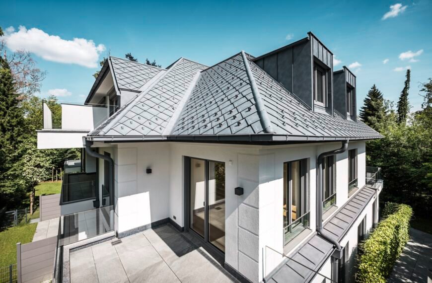 Weißes Haus mit grauem Aluminiumdach bei blauem Himmel und Sonnenschein
