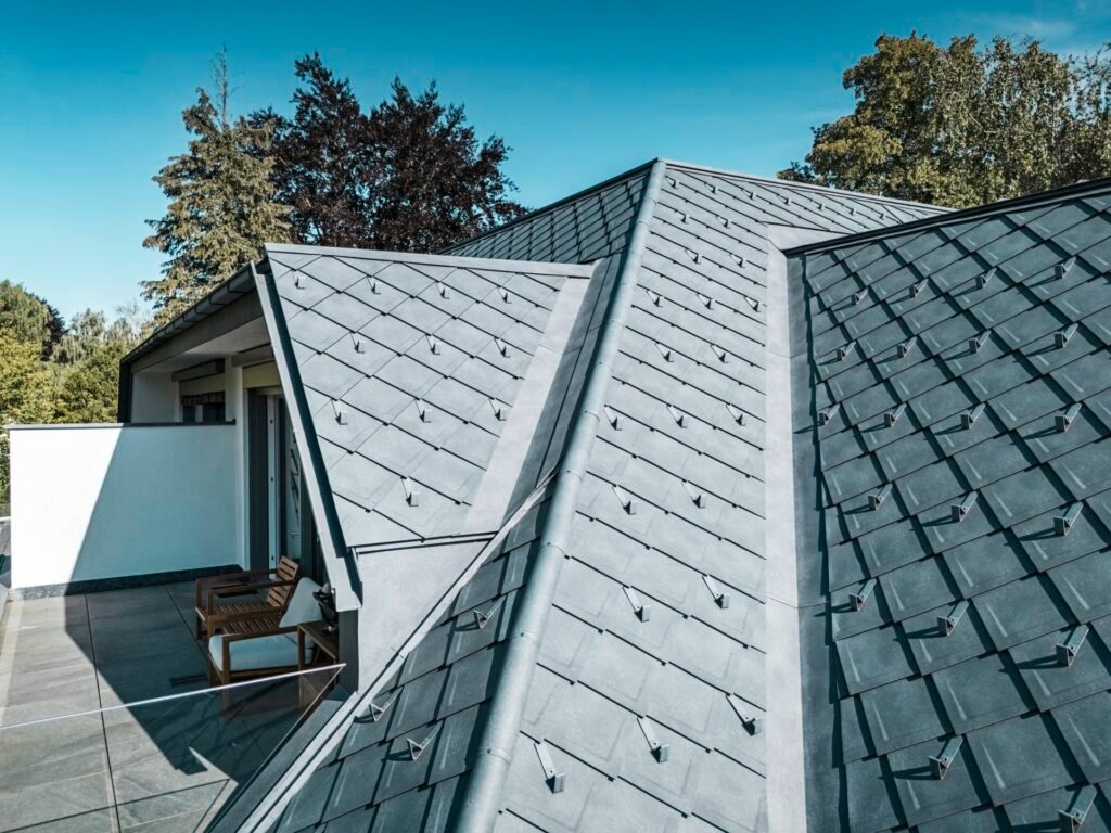 Nahaufnahme eines grauen Aluminiumdachs aus Aluminiumrauten bei blauem Himmel und Sonnenschein