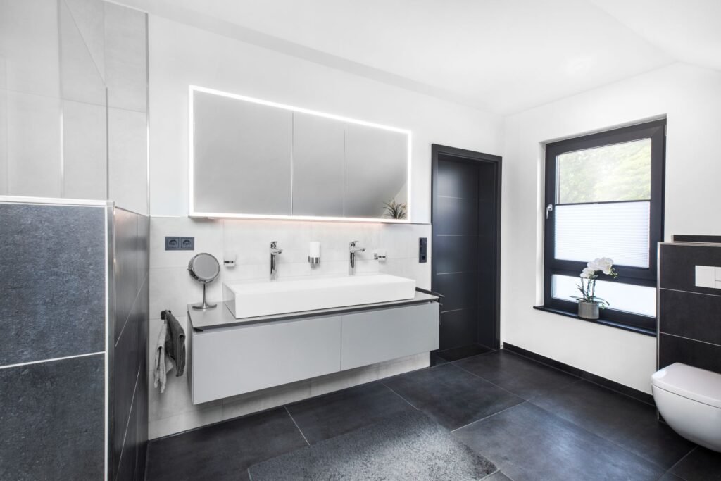 Badezimmer mit schwarzen Fliesen und weißen Sanitäranlagen