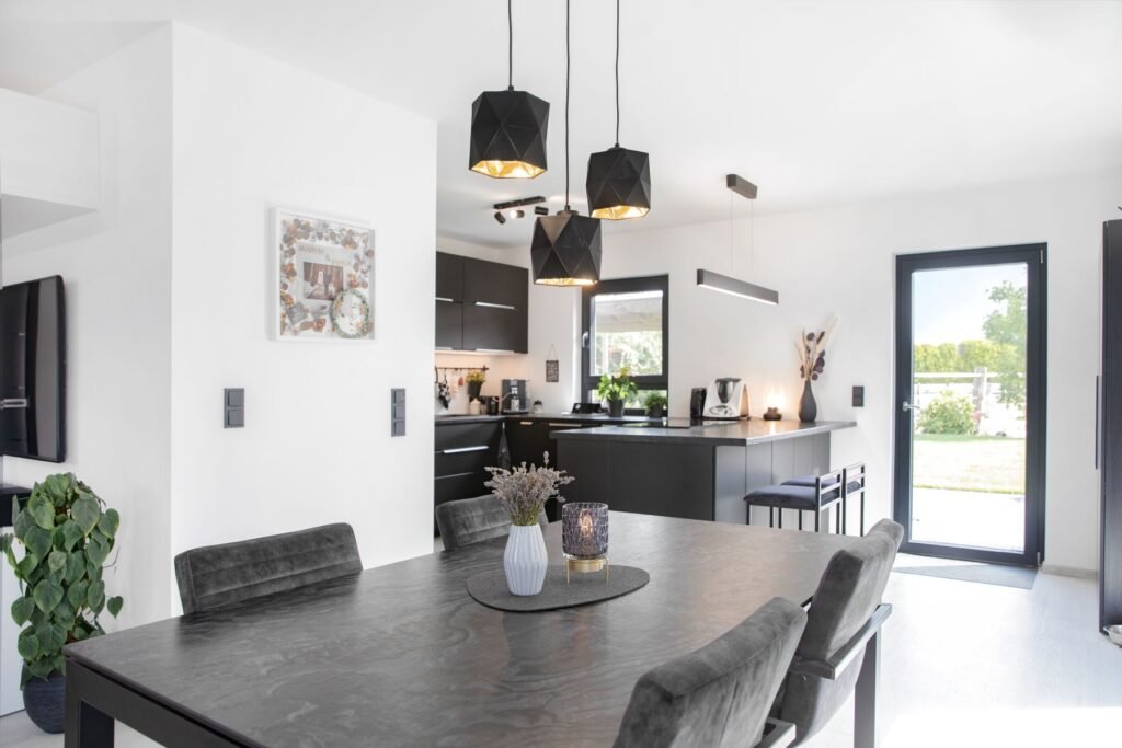 Esszimmer und Blick zur Küche mit weißen Wänden und schwarzen Möbeln