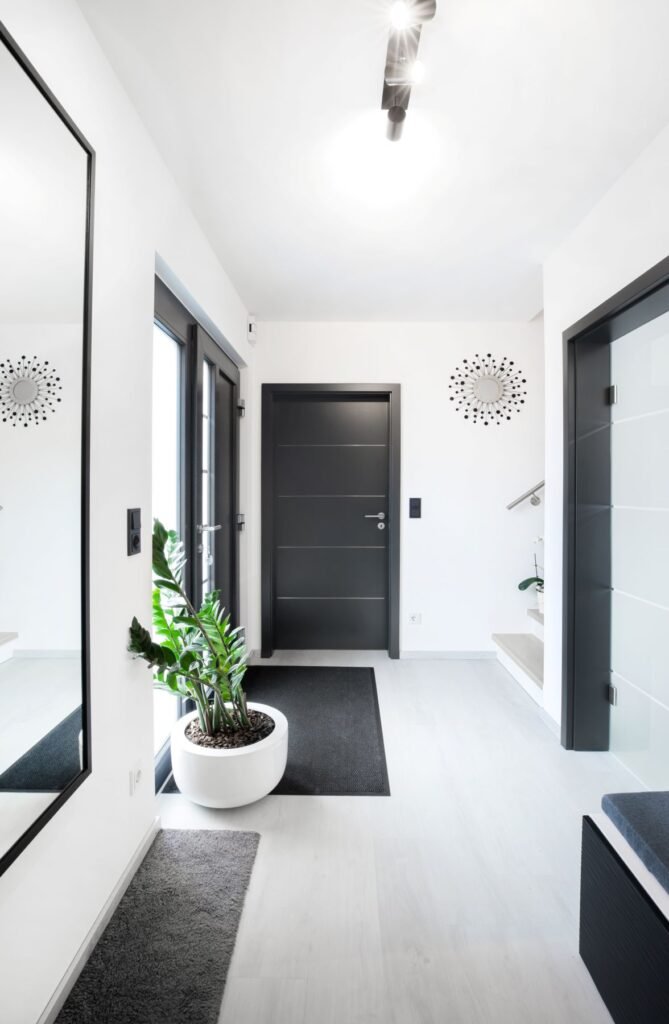 Flur mit weißen Fliesen und schwarzen Fenster und Türrahmen