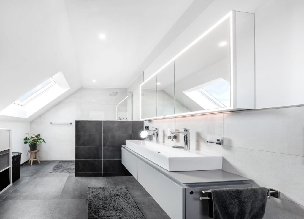 helles Badezimmer mit schwarzen Fliesen und weißen Sanitäranlagen