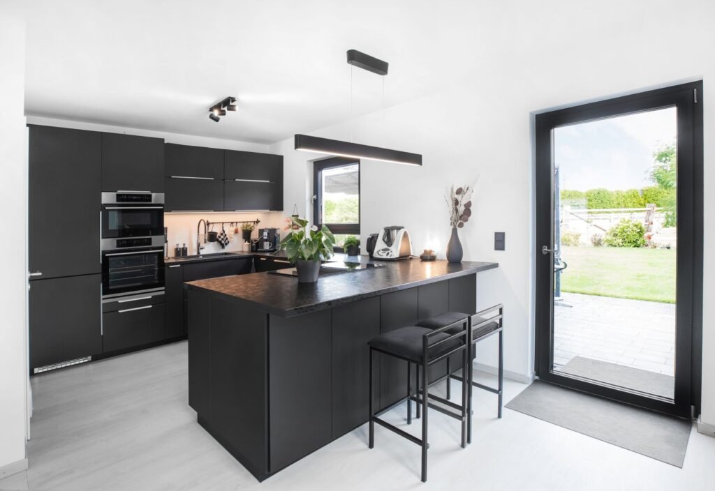 schwarze Küche mit weißen Wänden und dunkle Fensterrahmen