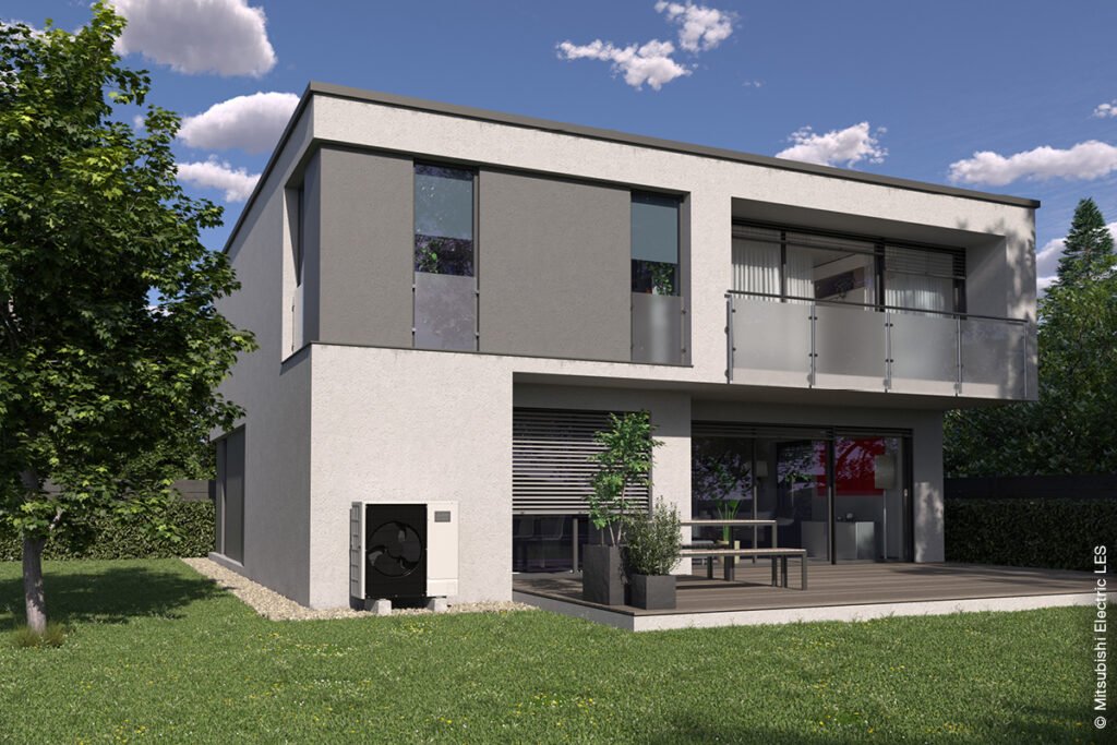Ein grau-weißes Bauhaus-Mehrfamilienhaus mit zwei Etagen, in einem grünen Garten bei strahlend blauem Himmel. An der Hauswand in der Nähe der Terrasse steht eine Mitsubishi Wärmepumpe.
