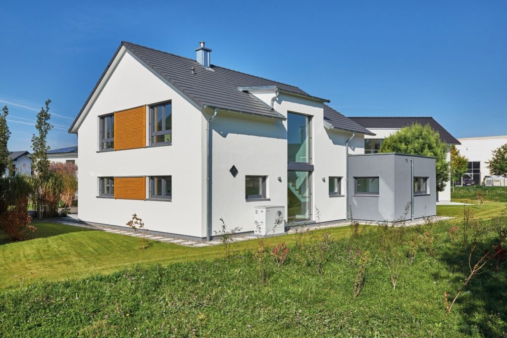 Musterhaus Günzburg Fertighaus Weiss Haus von außen Gartenansicht mit Wärmepumpe