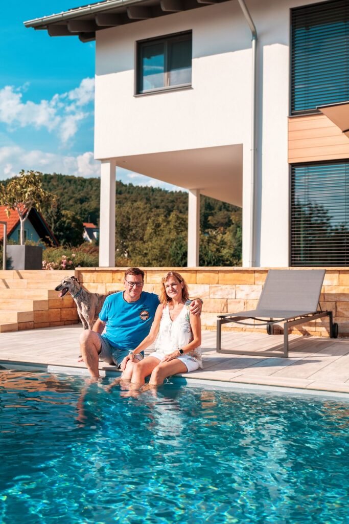 Weberhaus individuelles Architektenhaus Bauherren Paar vor dem Haus im Pool mit Hund
