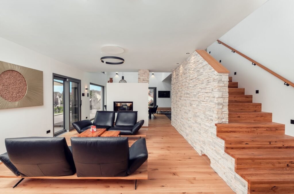 Weberhaus individuelles Architektenhaus Wohnbereich mit schwarzen Ledersofas und Treppenaufgang