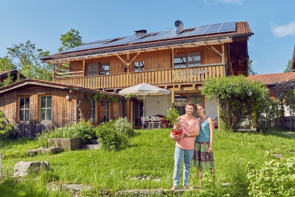 Paar steht im Grünen, vor süddeutsch geprägtem land- oder Bauernhaus