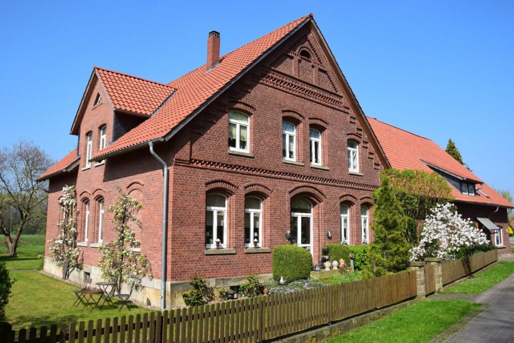 Historisches Bauernhaus mit dekorativer Backsteinfassade in blühendem Garten.