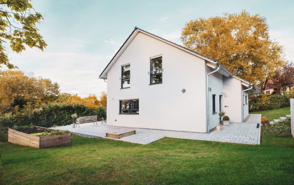 Außenaufnahme des Einfamilienhauses Vinaro von Fingerhut Haus, die eine Übereckansicht der Eingangsfassade und der westlichen Giebelfassade zeigt.