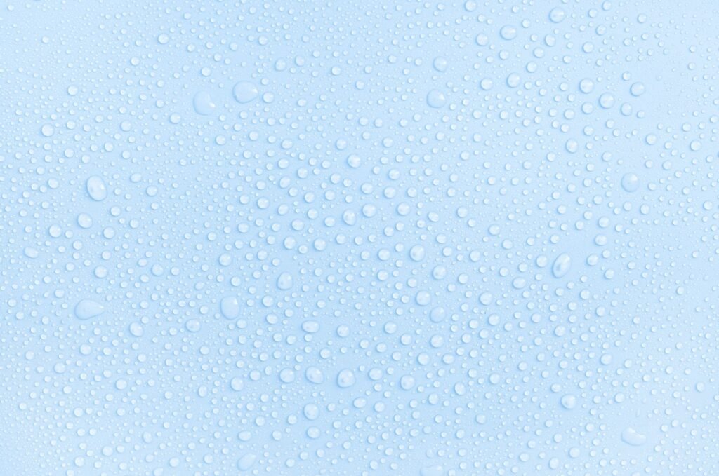 Detailaufnahme einer hellblauen Fläche mit Kondenswassertropfen
