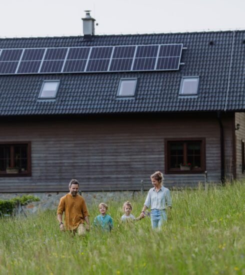 Eine Familie spaziert über das Grundstück vor ihrem Haus mit Solarpaneelen auf dem Dach. Foto: halfpoint/www.elements.envato.com