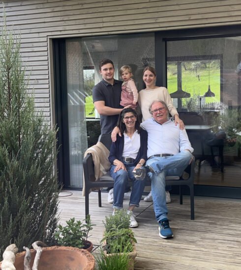 Alle drei Generationen der Bauherrenfamilie sitzen auf der Terrasse des neuen Baufritz-Bungalows