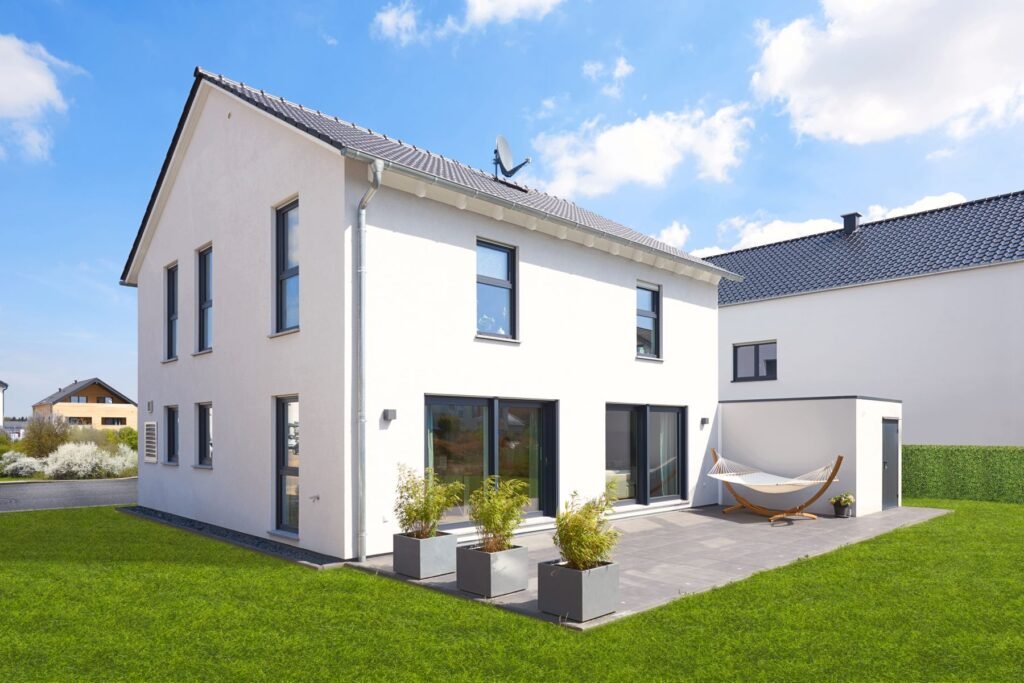 Haus Juna weiße Fassade mit Terrasse und Rasenfläche