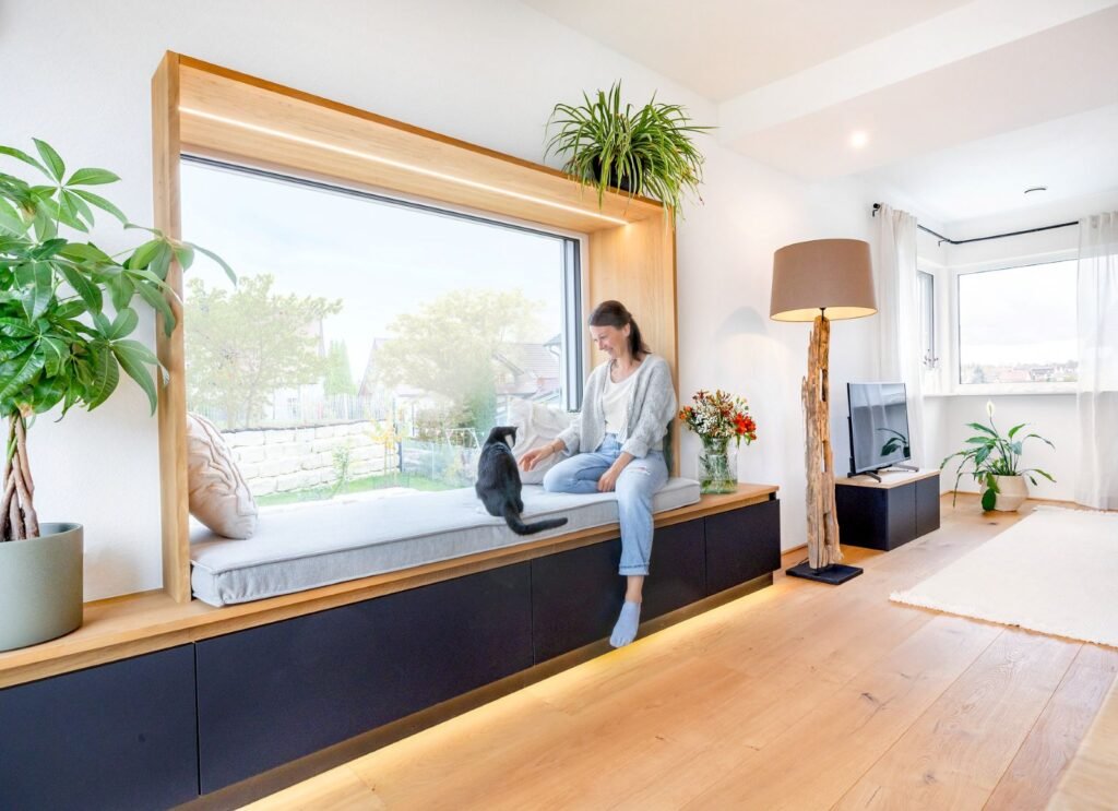 Schwörer Haus Heigl Wohnzimmer mit großem Sitzfenster Frau und Katze