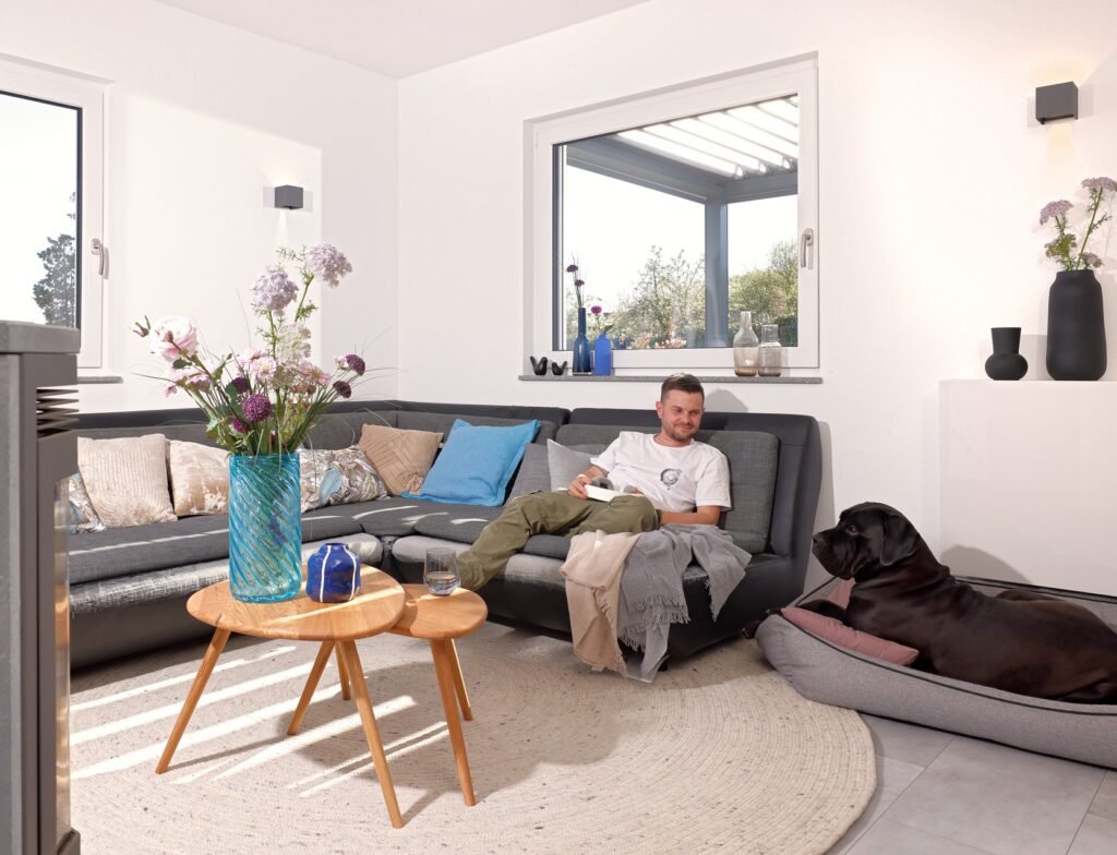 Schwörer Haus Rampf Wohnzimmer Mann auf dem Sofa und Hund im Körbchen