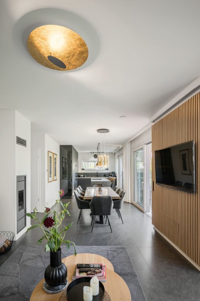 Weberhaus Graling Esszimmer aus der Sicht vom Wohnbereich mit Holzwand und TV