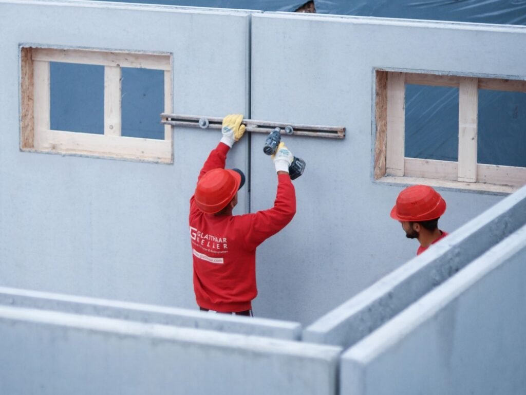 zwei Arbeiter auf der Baustelle eines Keller Rohbaus arbeiten in Teamarbeit Glatthaar