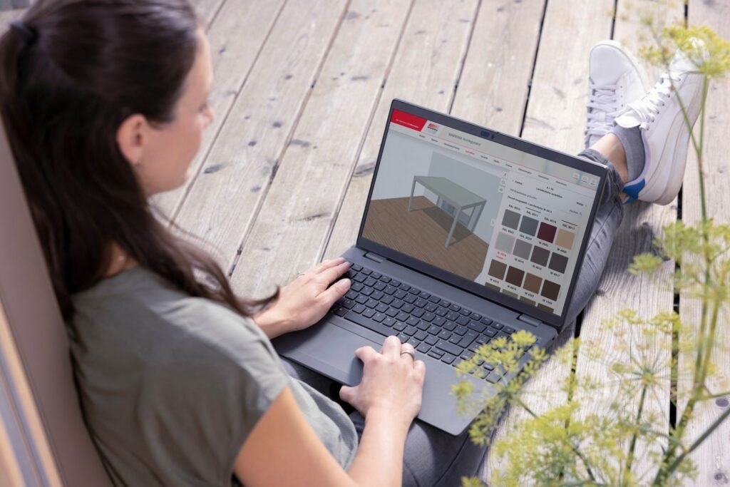 Frau sitzt mit Laptop auf dem Terrassenboden und bedient den Warema Konfigurator