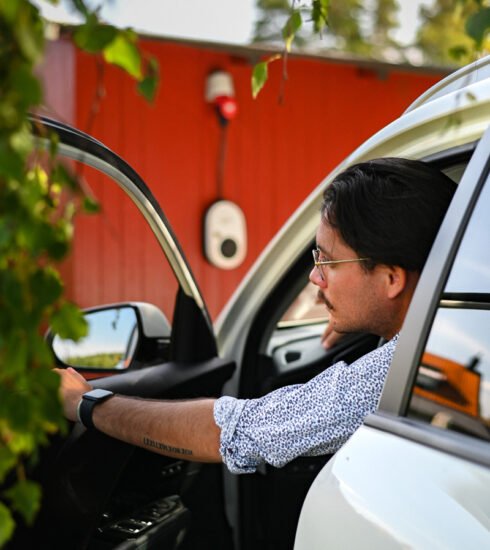 go e Mann in Auto und Wallbox an der Hauswand