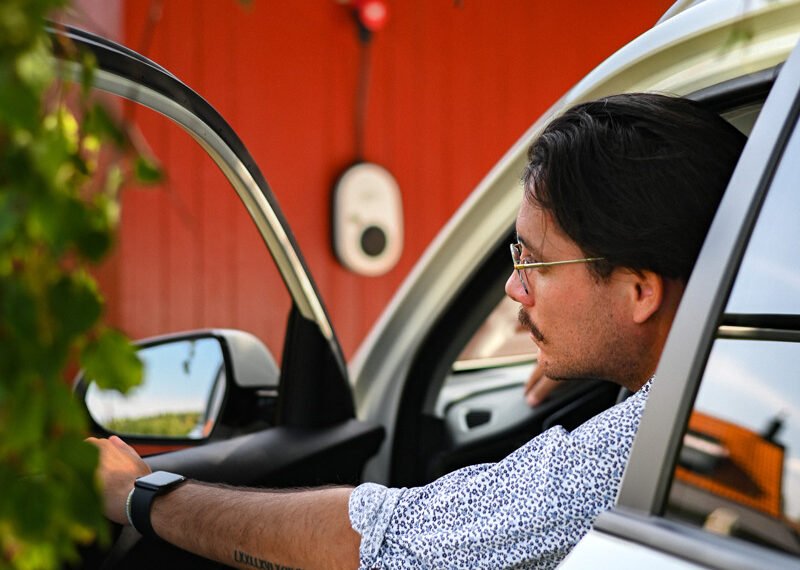 go e Mann in Auto und Wallbox an der Hauswand