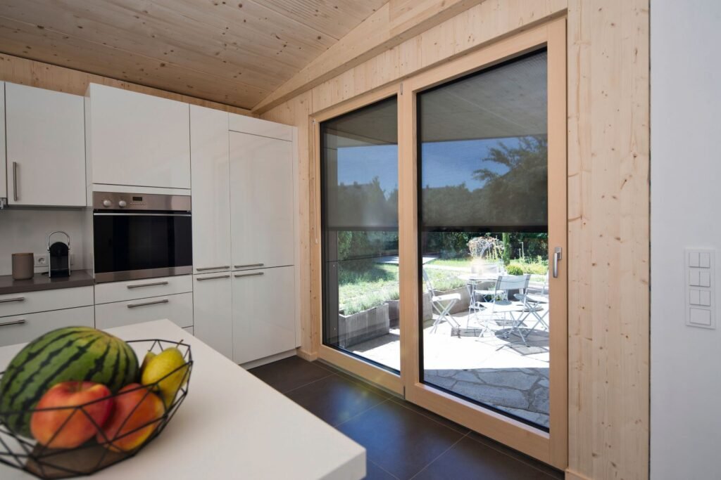 moderne Küche mit hellen Fronten und verglaster Tür zur Terrasse mit Warema Fenstermarkise